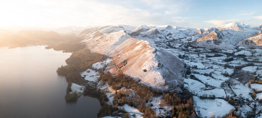 Beautiful morning light cast over Catbells with a fresh blanket of Snow.  Panorama of Mountains in the Lake District during Winter. 