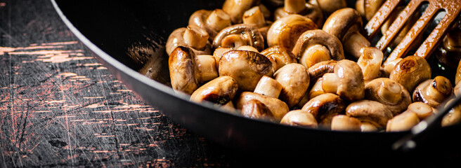 Small fried mushrooms in a frying pan. 