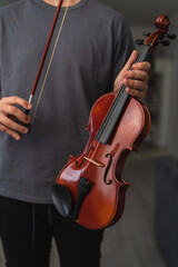 A portrait of a young guy playing or learning a violin in his home private classes online course for violin music