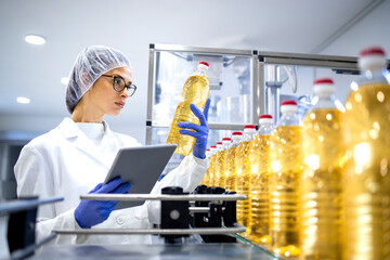 Food inspector or technologist doing quality control of bottled vegetable oil inside bottling plant.