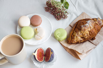 aesthetics of a cup of coffee, figs, a large croissant and macarons on a white background, top view