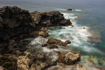 Obraz premium Rays of sunlight illuminating a volcanic cliff in the Atlantic Ocean.