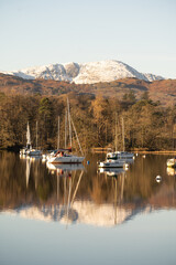 Beautiful Morning at Ambleside Pier.  Perfect reflections on lake Windermere, boats and snowy mountains in the background