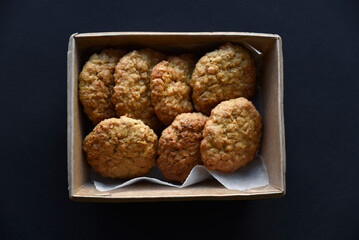 Delicious oatmeal cookies in a cardboard box on a black background. Sweet cookies. A sweet snack for tea.