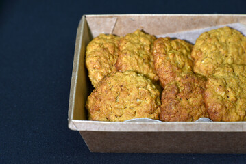 Delicious oatmeal cookies in a cardboard box on a black background. Sweet cookies. A sweet snack for tea.