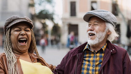 Happy multiracial senior couple having fun in city - Elderly people and love relationship concept