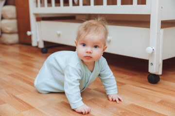 a funny baby crawling in the nursery at home. the baby is 6 months old learning to crawl