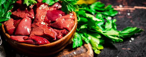 Pieces of raw liver in a bowl on a parsley cutting board.