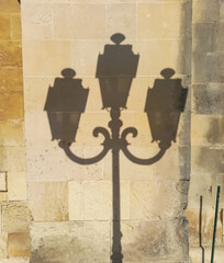 silhouette of Victorian three light cast iron streetlight against honey stone in Corfu street.