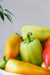 Sweet peppers. A fresh crop of colorful peppers on a plate on the edge of the table. Light background.