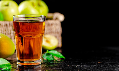 A glass of green apple juice with leaves on the table. 