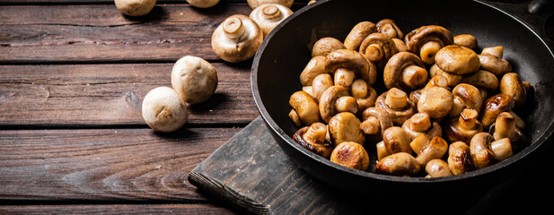 Fragrant homemade fried mushrooms in a frying pan on a cutting board. 