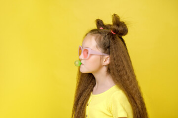 Cool cute girl with a trendy hairstyle and pink sunglasses with bright emotionson a yellow background
