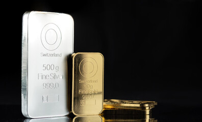 A 500 gram silver bar and several gold bars on a black background.
