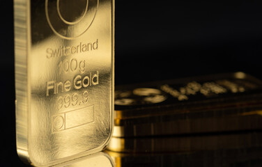 Ingot of gold weighing 100 grams on a black background. Selective focus.