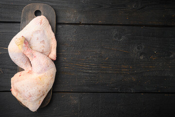 Chicken brow and drumstick with skin, on wooden cutting board, on black wooden table , top view flat lay, with copy space for text