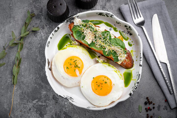 Two fried eggs for breakfast with avocado toast and salad on a plate. Healthy breakfast on the table, top view