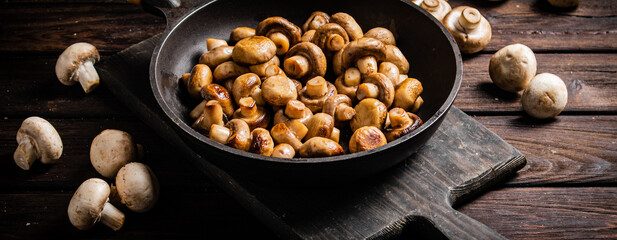 Fragrant homemade fried mushrooms in a frying pan on a cutting board. 
