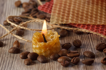 a burning natural wax candle, on the background natural wax with honeycombs and a wick