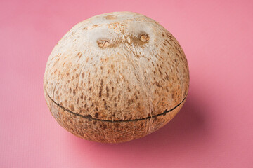 Whole ripe fresh Coconut, on pink textured summer background