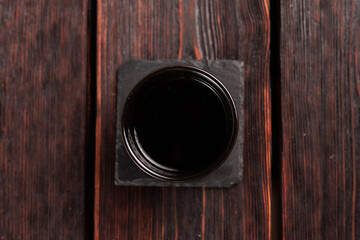 Bowl with soy sauce on wooden table, top view