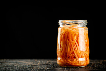 A glass jar with canned carrots. 