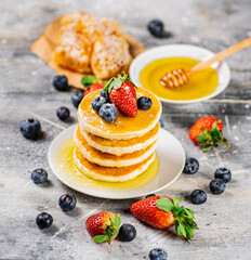 Pancakes in a plate with berries and honey. 