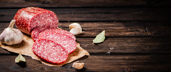 Pieces of salami sausage with garlic and bay leaf on paper. 
