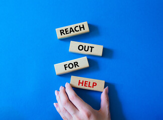 Reach out for help symbol. Wooden blocks with words Reach out for help. Businessman hand. Beautiful blue background. Business and Reach out for help concept. Copy space.
