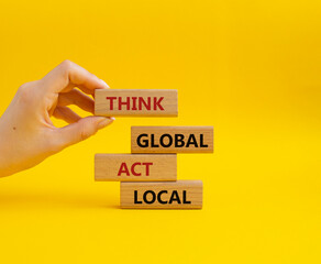 Think global act local symbol. Wooden blocks with words Think global act local. Beautiful yellow background. Businessman hand. Business and Think global act local concept. Copy space.