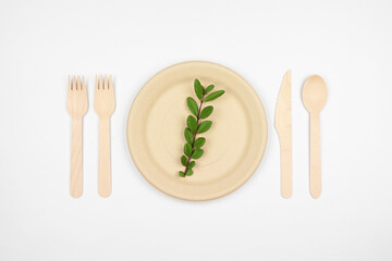 Eco friendly disposable dishware. Above view place setting with plates and cutlery on a white background. Biodegradable, composable alternative to plastic.