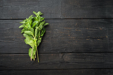 A bunch of mint, spearmint or peppermint, on black wooden table background, top view flat lay, with copy space for text