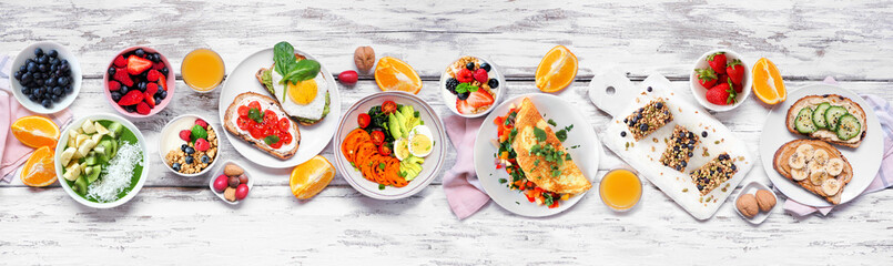 Healthy breakfast food table scene. Top down view over a white wood banner background. Omelette,...