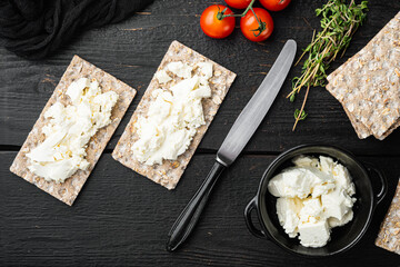 Crisp bread with cream cheese, on black wooden table background, top view flat lay