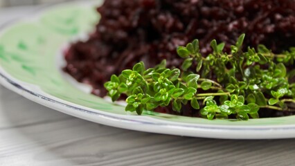 sprig of thyme seasoning on the background of a plate with red chopped beets