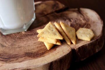 there is a glass of milk and a small lean cookie on a wooden stand