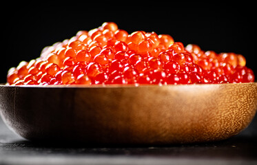 Red caviar in a wooden plate. 