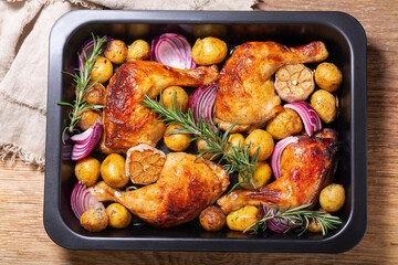 Chicken legs with potatoes and rosemary in a baking dish, top view