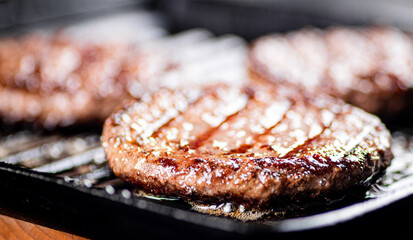 Cooking a delicious grilled burger on a pan with oil bubbles.