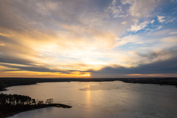 Golden hour over the frozen lake. Golden sunset over the frozen lake. Sunset reflection in water. Winter sunset over lake.