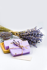 lavender soap in wooden soap dish with dry lavender flowers and bouquet on white background