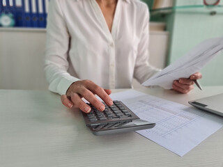 Woman using calculator and calculating bills at home office