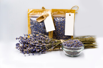 dry culinary  lavender in two transparent bags with dry lavender flowers in glass plate and violet bouquet on white background