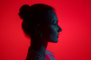 Dark woman profile portrait on red background with copy space. Lights play.