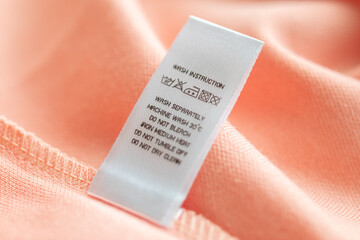 White laundry care washing instructions clothes label on pink cotton shirt