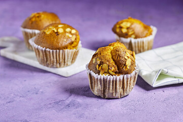 Vanilla Caramel Nuts Muffins In Paper Cups On purple background