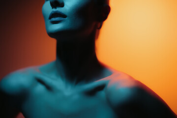 Fashion woman profile portrait on orange gradient background with soft blue light play on skin. Lights play.