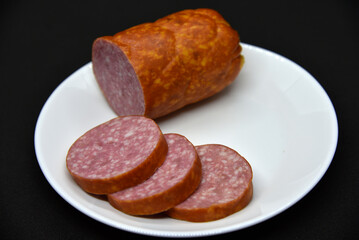 Delicious meat sausage on a white plate. Sliced ham. Slices of meat.
