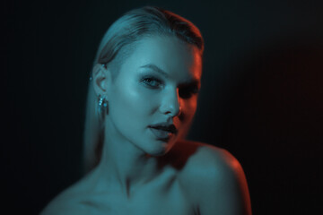 Fototapeta premium Fashion woman portrait on dark background with soft blue and red lights play on skin and copy space.