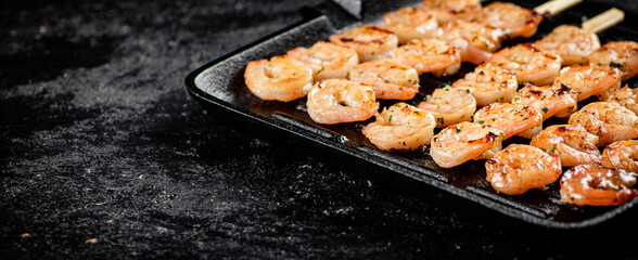 Shrimp on skewers are grilled in a grill pan. 